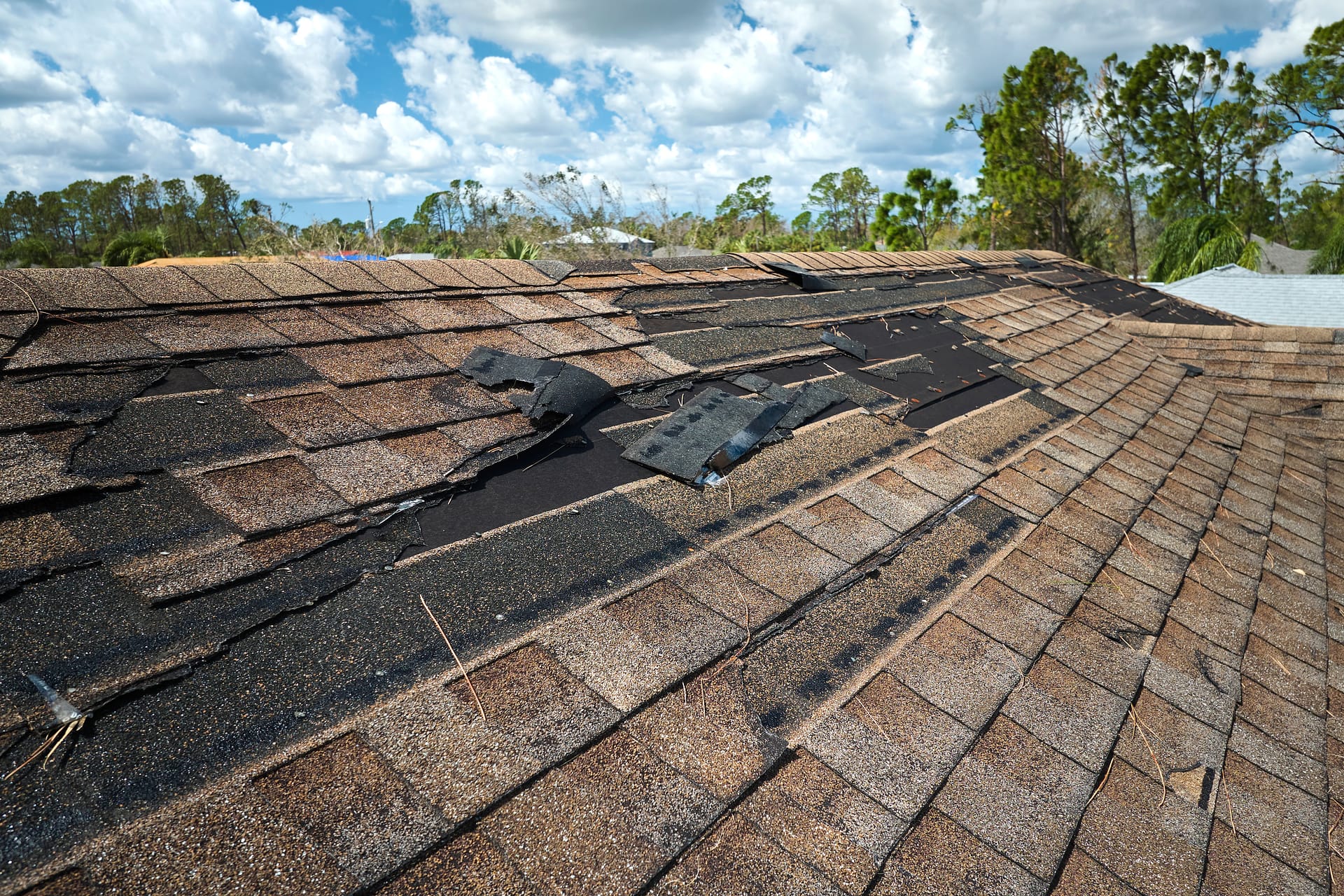 Damaged house roof with missing shingles after hurricane Ian in Florida. Consequences of natural disaster Damaged house roof with missing shingles after hurricane Ian in Florida. Consequences of natural disaster.