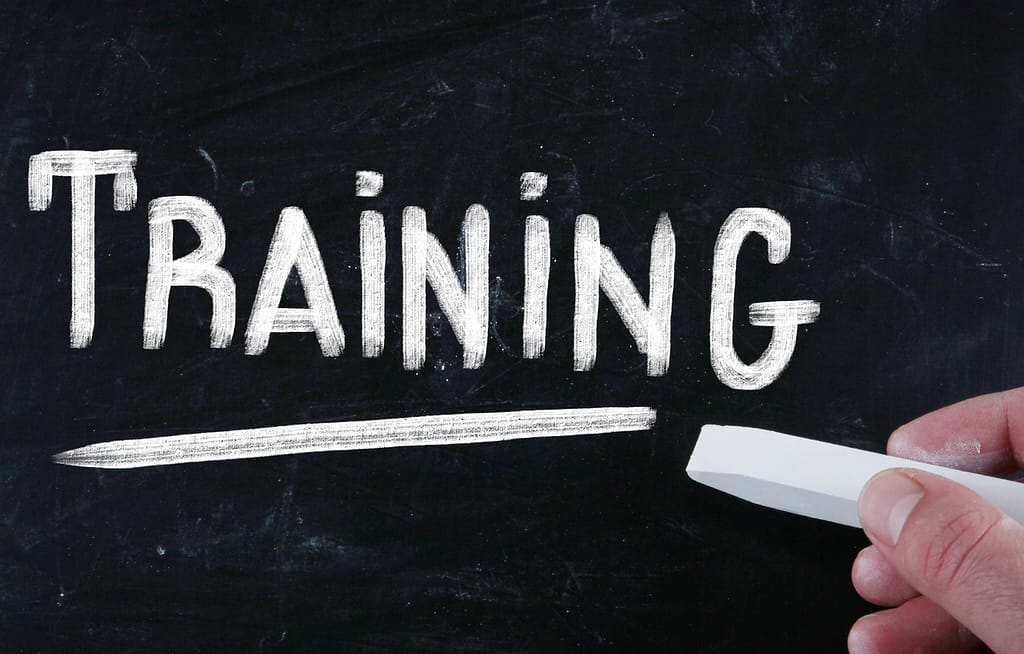 a hand writes the word training with chalk on a chalkboard, focusing on Why Contractor Training Matters