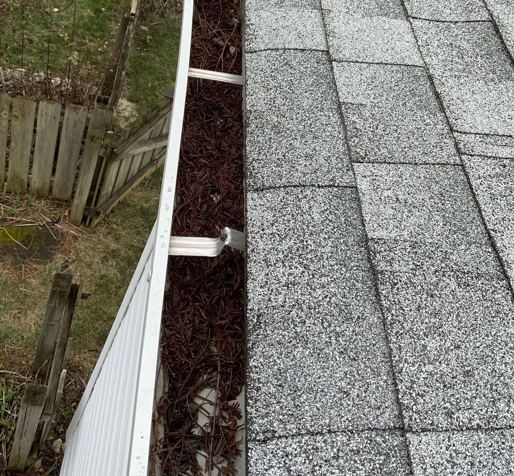 picture of a clogged gutter, reminding the homeowner of the importance of spring gutter cleaning.