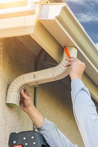 Worker Attaching Aluminum Rain Gutter and Downspouts to Fascia
