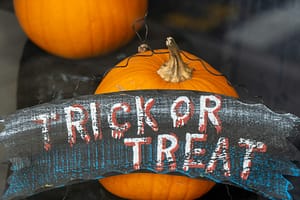 A house window celebrating Halloween with a Trick-or-Treat sign