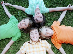 four kids in a circle on green grass having fun at a one of the Columbus Ohio area summer camps.