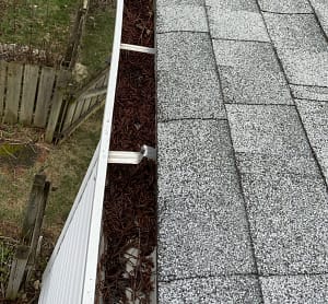picture of a clogged gutter, reminding the homeowner of the importance of spring gutter cleaning.
