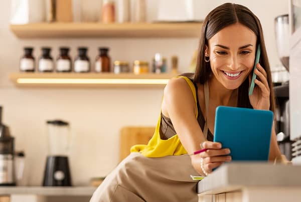 small business owner looking at her tablet while on the phone