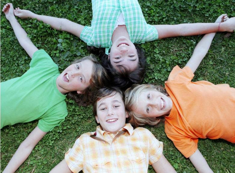 four kids in a circle on green grass having fun at a one of the Columbus Ohio area summer camps.