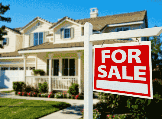 The image shows a "For Sale" sign in front of a house, indicating that the property is on the market. When selling should your repair your roof or leave it as is.